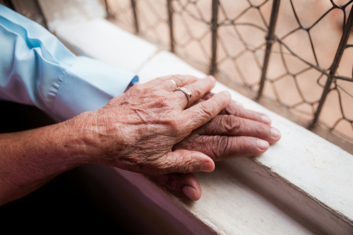 A younger person holding the hand of an older person